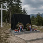 Spomenik u Vinjanima prekriven tamnim platnom uz bijeli križ, vijence i lampione kao simbol neriješenih pitanja odgovornosti prema poginulim hrvatskim braniteljima.